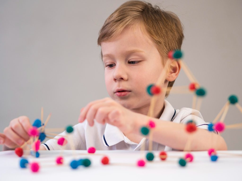 Enfant jouant avec un jeu éducatif de chimie à l’école, illustrant l’apprentissage scolaire et le développement cognitif en classe.