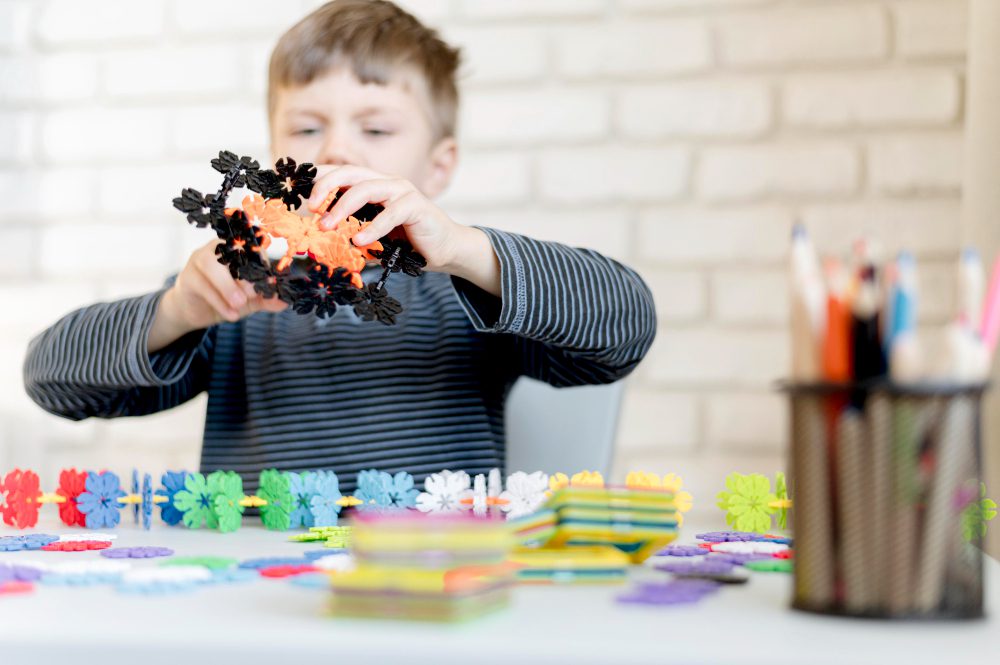 Un enfant assemble des pièces colorées et emboîtables sur une table, mettant en valeur le jeu manuel, la créativité et la construction de formes.