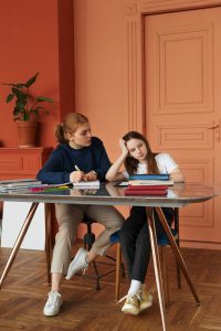 Jeune femme visiblement épuisée et distraite à son bureau, accompagnée d'une collègue, illustrant les signes du TDAH chez l'adulte non diagnostiqué.