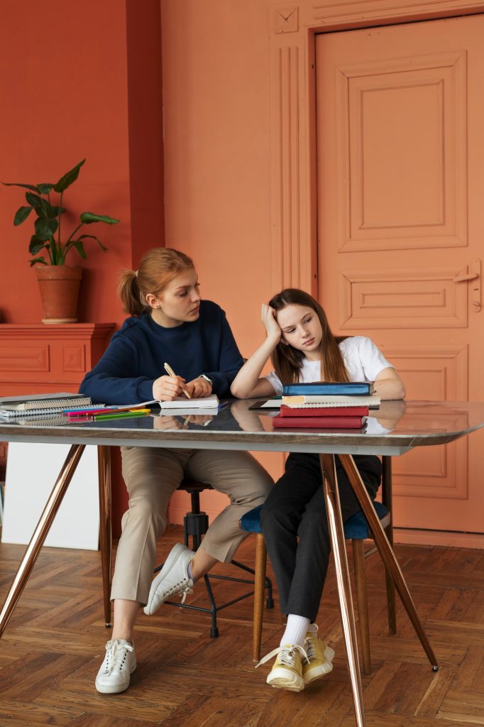 Jeune femme visiblement épuisée et distraite à son bureau, accompagnée d'une collègue, illustrant les signes du TDAH chez l'adulte non diagnostiqué.