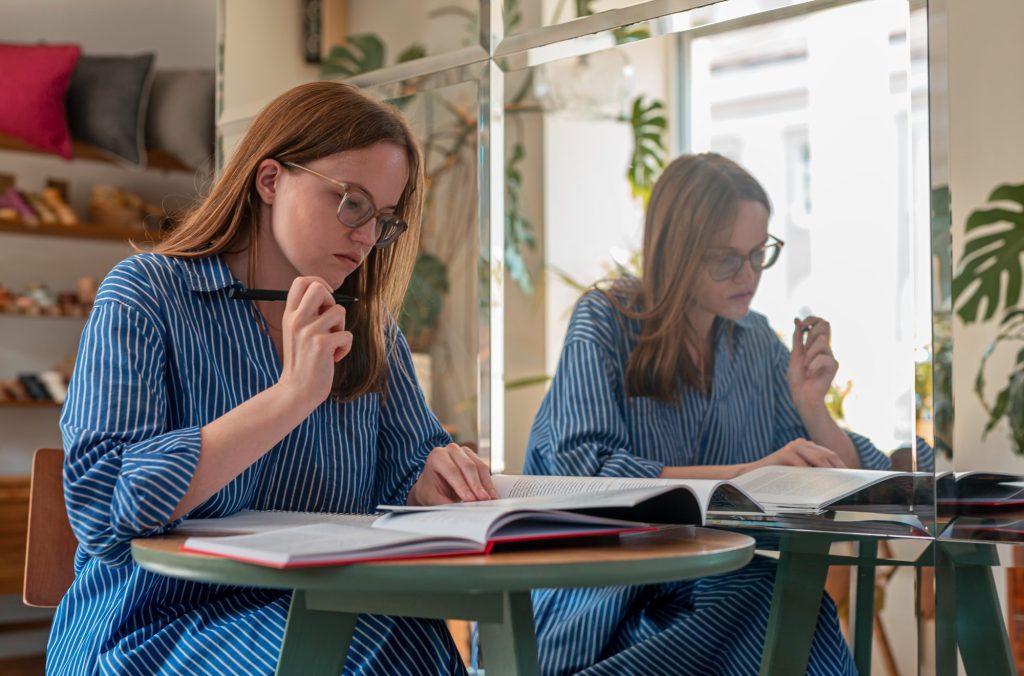 Deux femmes adultes lisent attentivement un livre ouvert dans un café animé.