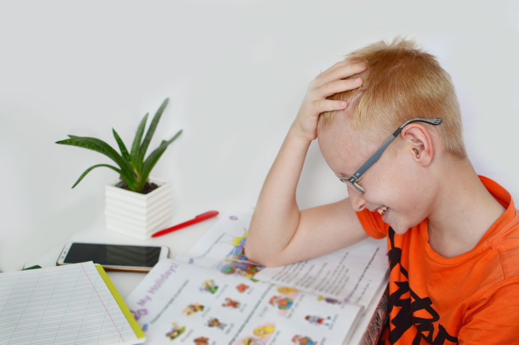 Un enfant d'âge scolaire en difficulté devant ses devoirs, illustrant les symptômes de la dyspraxie motrice au quotidien.