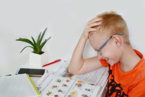 Un enfant d'âge scolaire en difficulté devant ses devoirs, illustrant les symptômes de la dyspraxie motrice au quotidien.