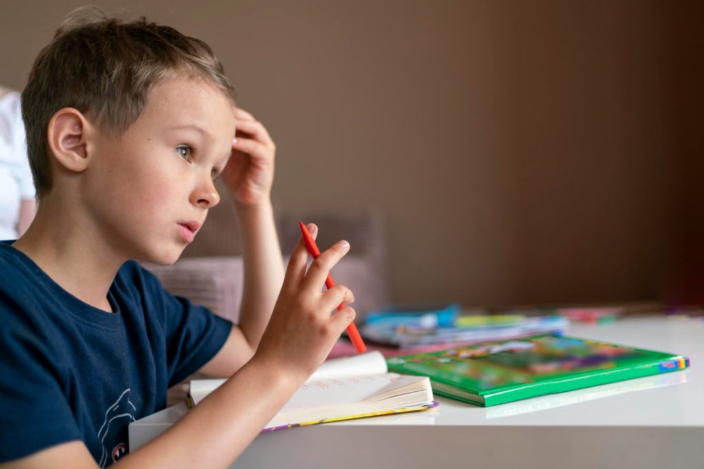Un jeune garçon concentré sur un livre ouvert, illustrant les signes d'alerte du diagnostic dyslexie chez l'enfant d'âge scolaire.