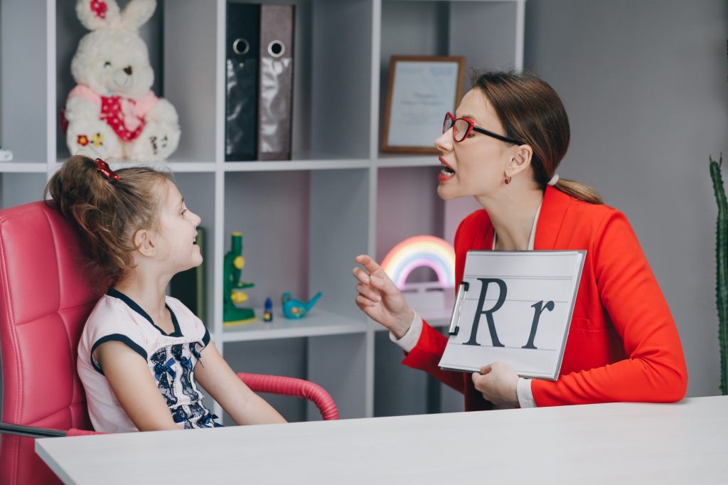 Une spécialiste présentant des lettres à une enfant lors d'un test de dyslexie évaluant la conscience phonologique au Québec.