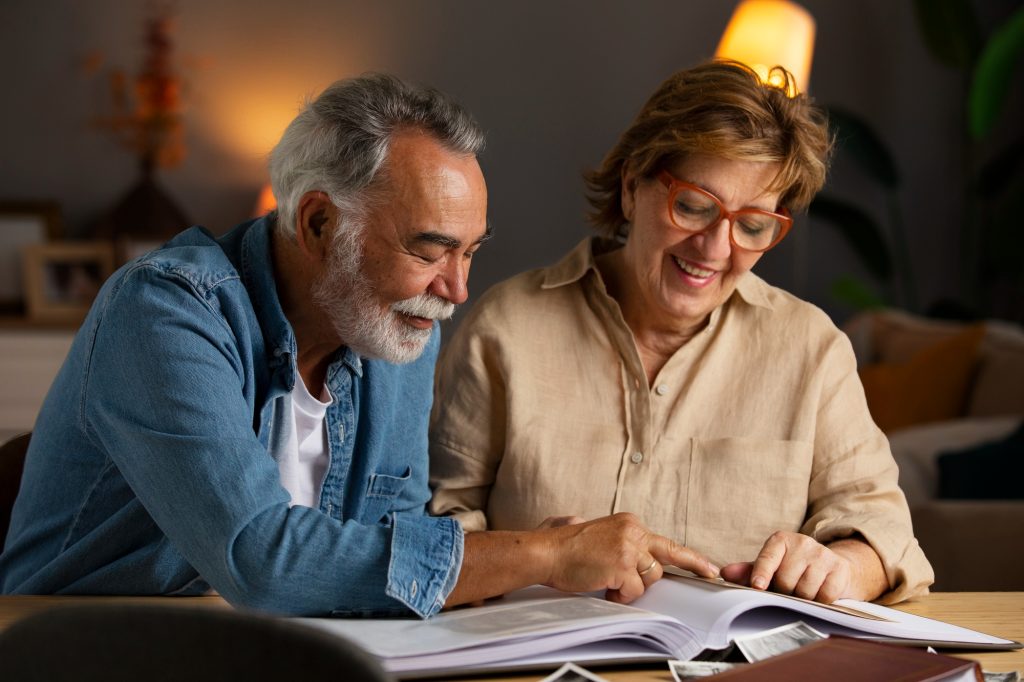 Couple d'âge mûr souriant, penché sur des documents consultés ensemble : compréhension d'un rapport d'évaluation neuropsychologique.