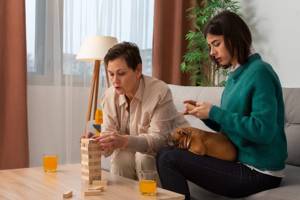 Deux femmes jouant ensemble à un jeu de blocs à la maison, illustrant la participation sociale et l'autonomie au quotidien chez les adultes autistes.