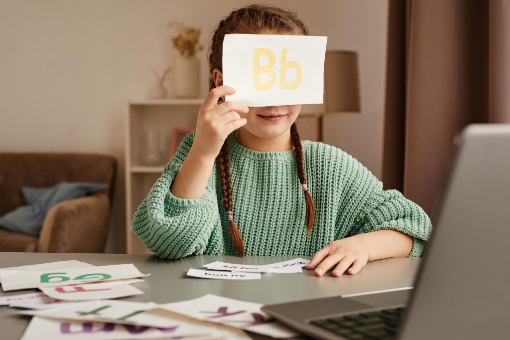La fillette tient une carte-lettre « Bb » lors d'un exercice d'accompagnement de la dyslexie chez l'enfant. 