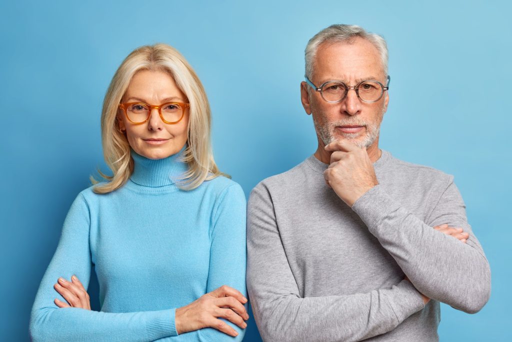  Femme et homme d'âge mûr, bras croisés et air songeur : reconnaître la douance à l'âge adulte soulève souvent bien des questions.