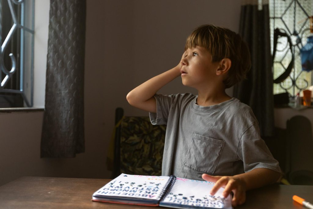 Enfant travaillant sur un cahier de lettres dans un contexte pédagogique lié à la dyslexie et à la dysorthographie.
